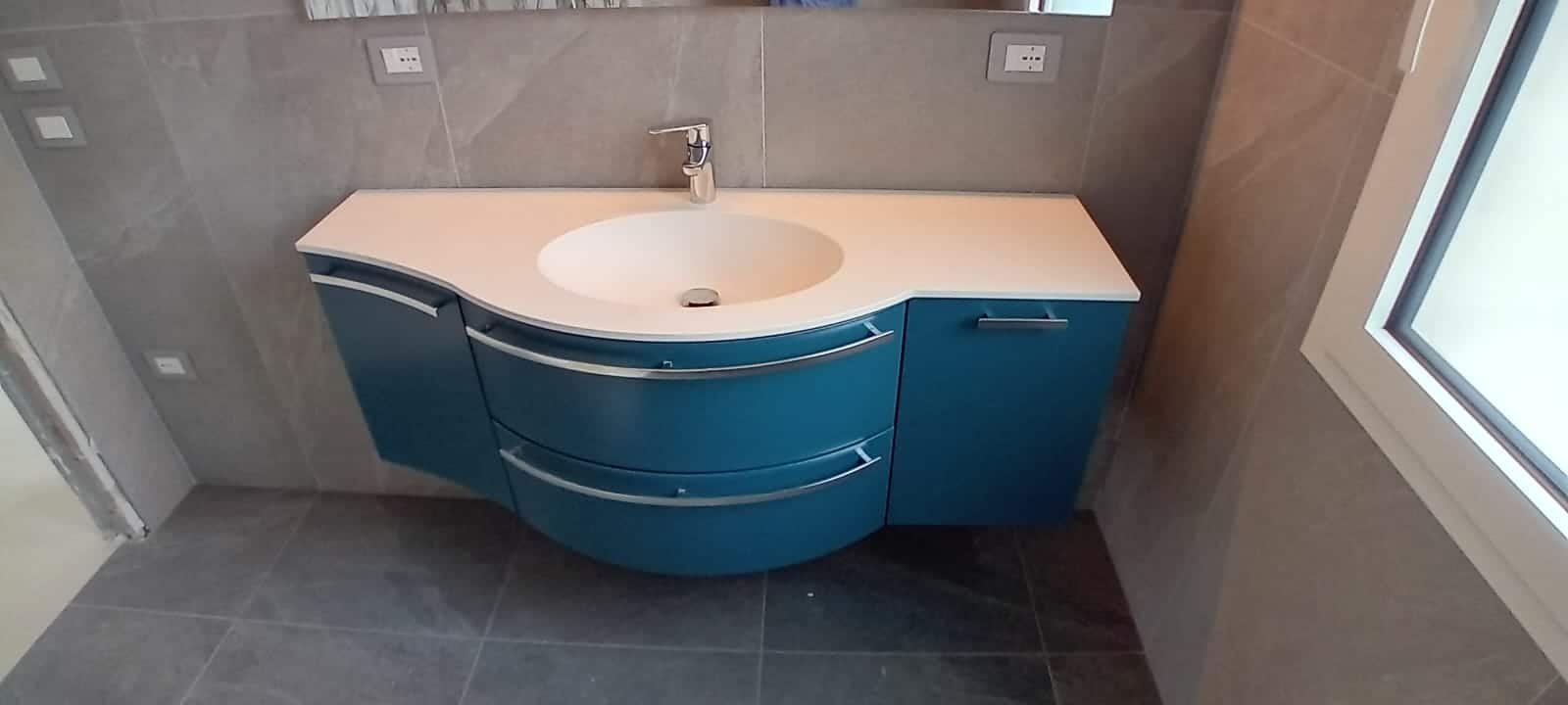Mobile bagno curvo Compab laccato lucido installato presso un nostro cliente, con lavabo integrato e specchiera.